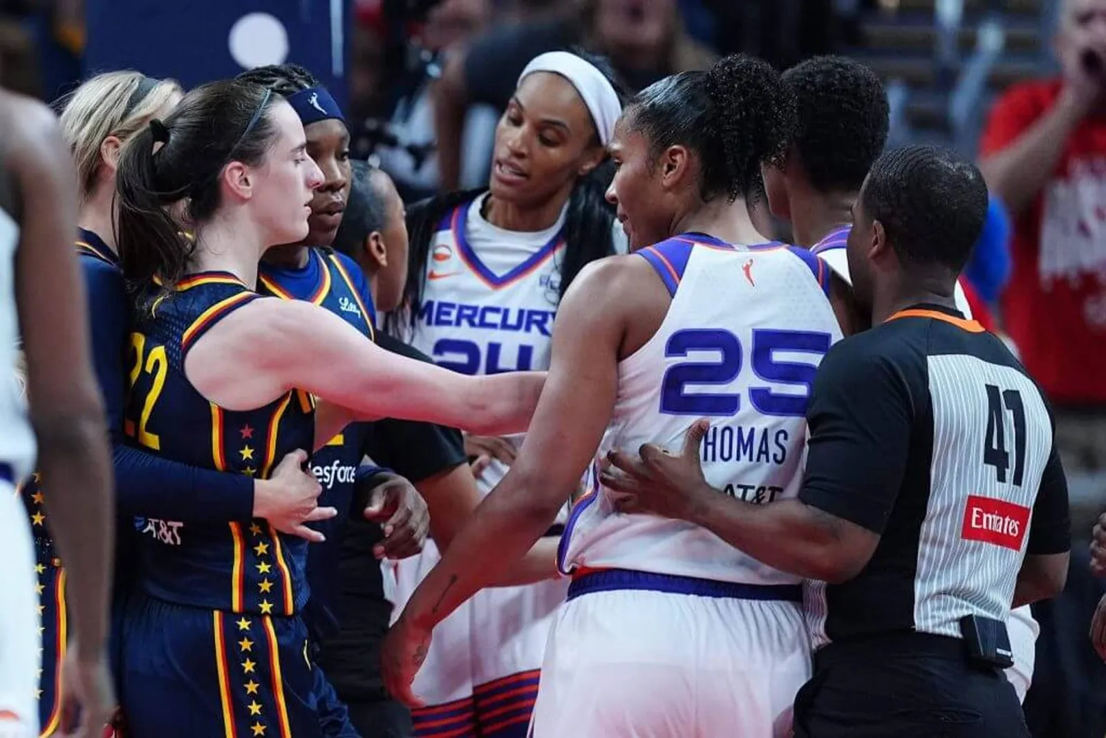 Indiana Fever guard Caitlin Clark, left, and Phoenix Mercury forward DeWanna Bonner, center, are separated by a referee during a skirmish in Monday's game.