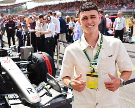 Phil Foden poses for a photo with the Audi F1 eam on the grid before the British Grand Prix